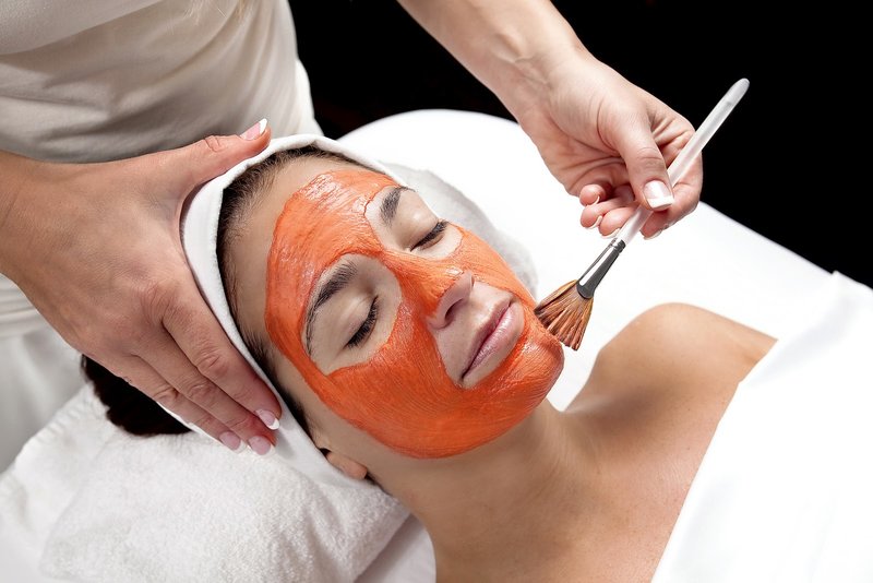 O mască de morcov este aplicată pe fața unei fete cu o perie