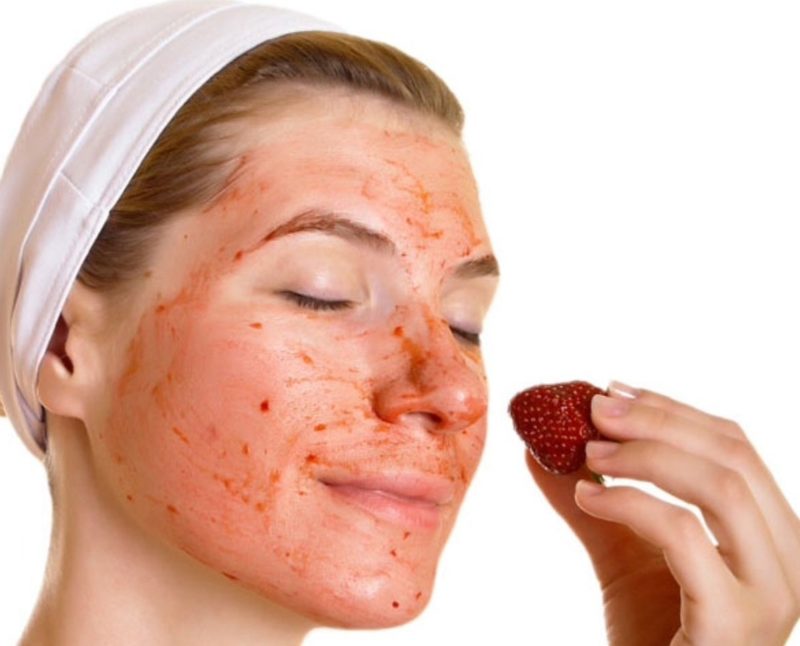 Fata își freacă fața cu suc de căpșuni
