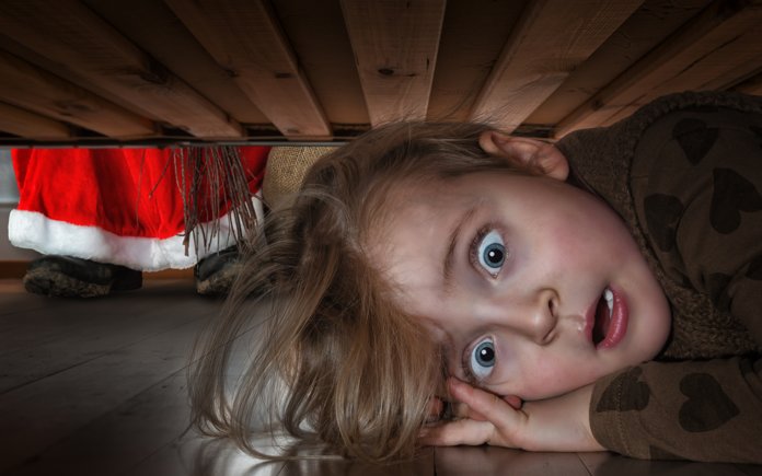 Skrekket baby som gjemmer seg under sengen