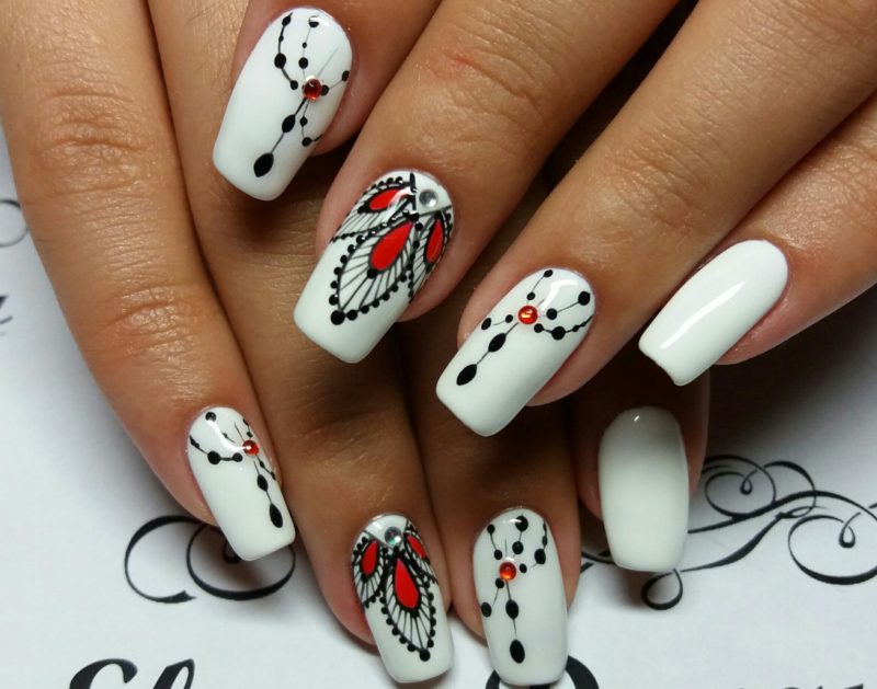 Witte nagels met zwarte en rode patronen