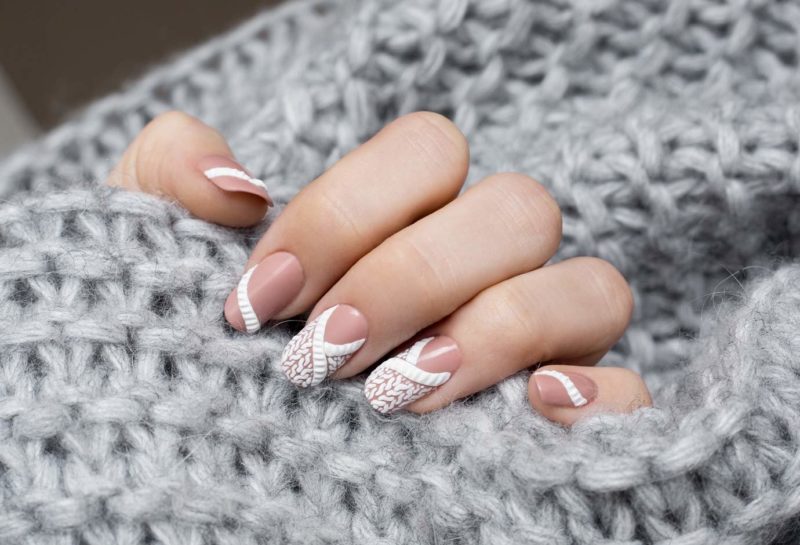 Wit gebreid patroon op nagels van gemiddelde lengte