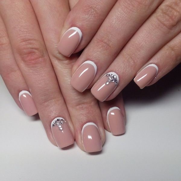 Naakt manicure met witte gaten en strass steentjes.