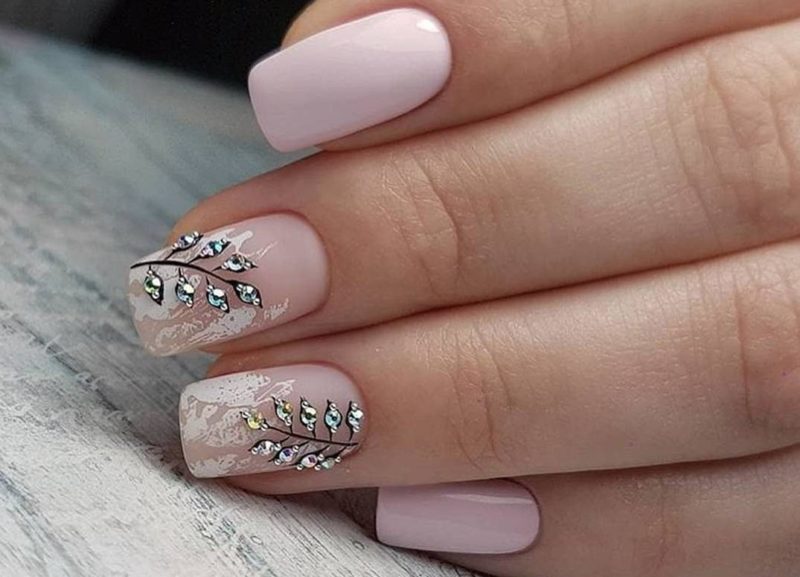 Roze manicure met bloemmotief en strass steentjes.
