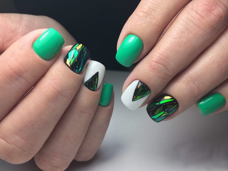 Groene manicure met gebroken glas en een driehoekig gat