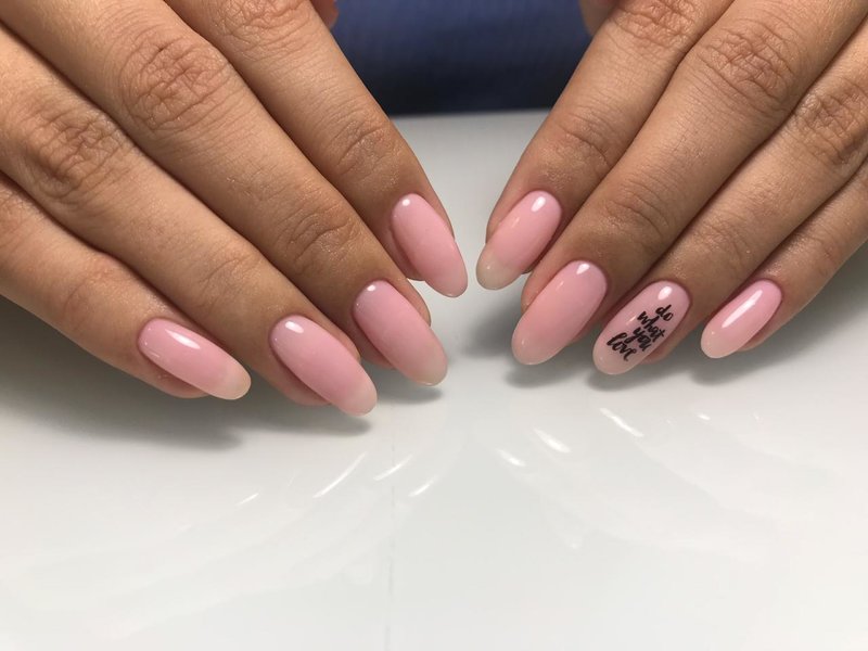 Delikatny różowy manicure z napisem.