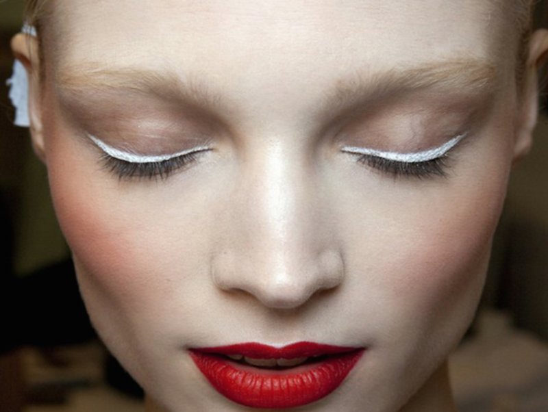 Maquillage minimaliste avec les flèches blanches à la mode et le rouge à lèvres.
