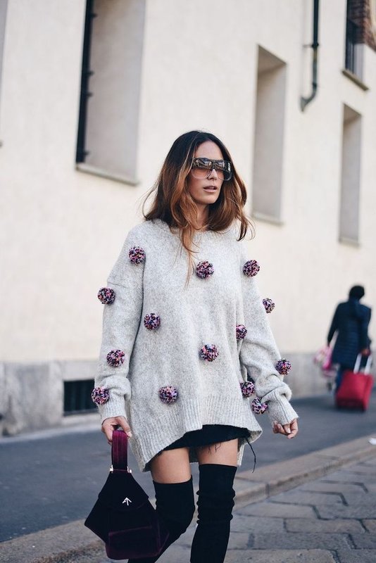 Jente i overdimensjonert genser med pomponger.