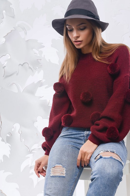Lány egy pulóvert, egyszerű pomponokkal