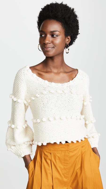 Fată într-un pulover cu pompoane și o fustă