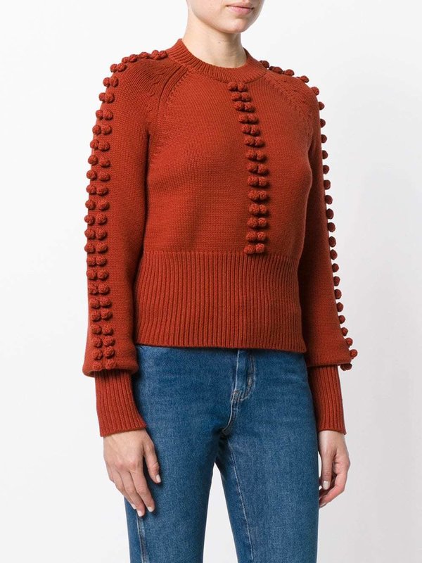 Lány egy pulóvert texturált pomponokkal