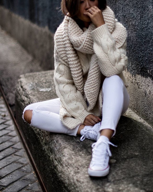 Lány egy nagy kötött pulóverben és széles gallérral