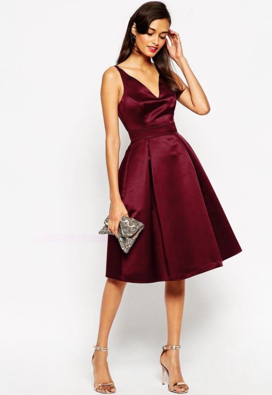 Fată într-o rochie de cocktail burgundy cu decolteu adânc