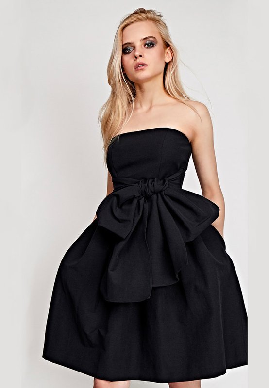 Dívka v černé koktejlové bandeau šaty s plnou sukni