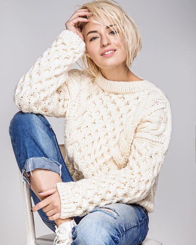 Dívka v těžkém pleteném svetru a džínách