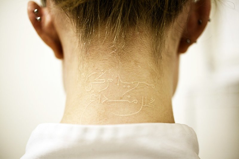 Witte tatoeage op de achterkant van het hoofd