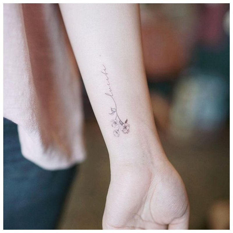 Lettrage avec fleur - tatouage au poignet