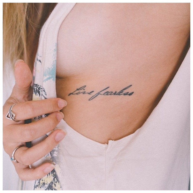 Napis pod tatuażem na piersi