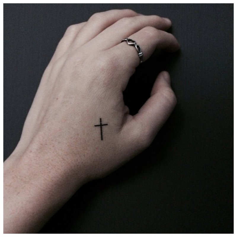 Een kleine tatoeage op de arm van de man in de vorm van een kruis