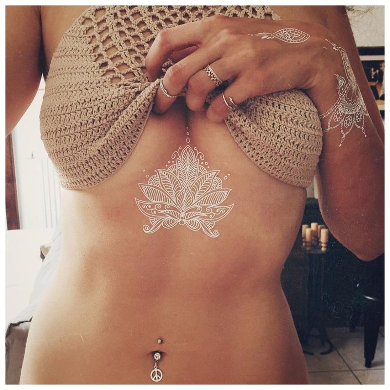 Witte mehendi-tatoeage onder de borst