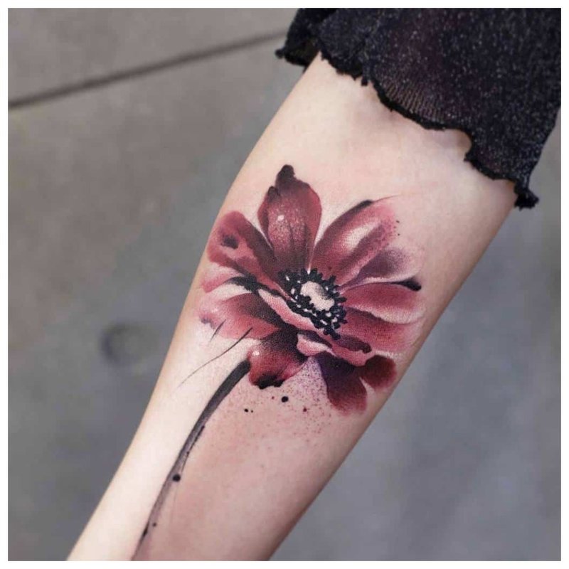 Aquarel tattoo in de vorm van een bloem op de arm
