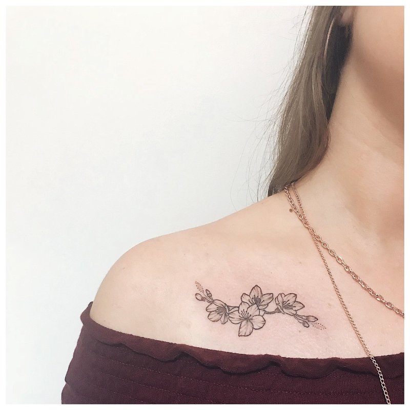 Tatuaje de flor de contorno debajo de la clavícula