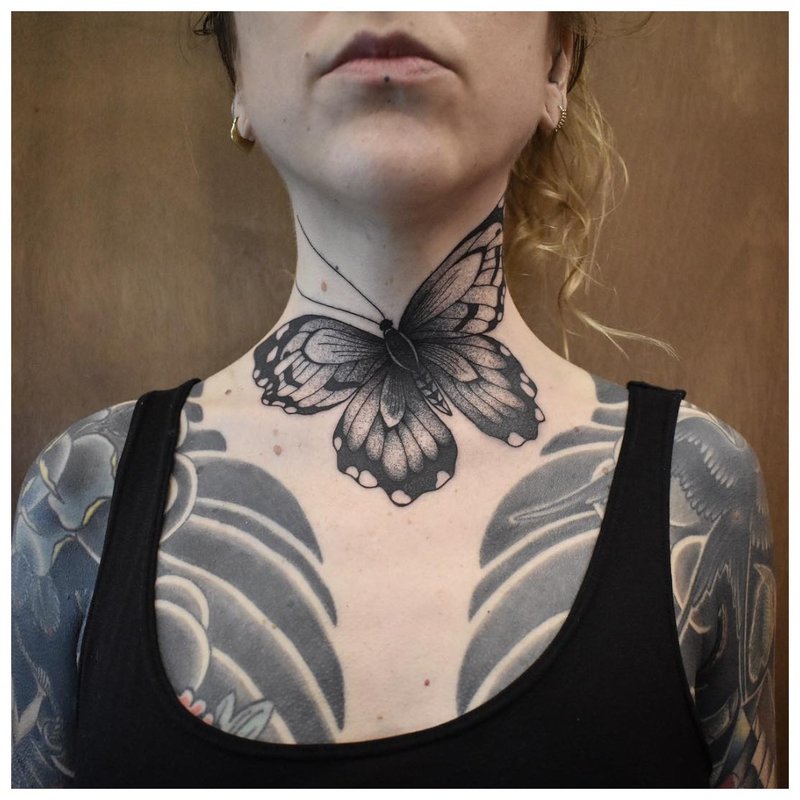 Large butterfly - a tattoo on the girl’s neck