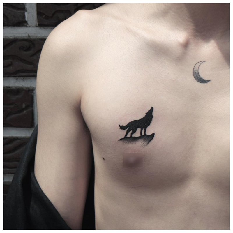 Wilk wyje na księżyc - tatuaż na piersi mężczyzny